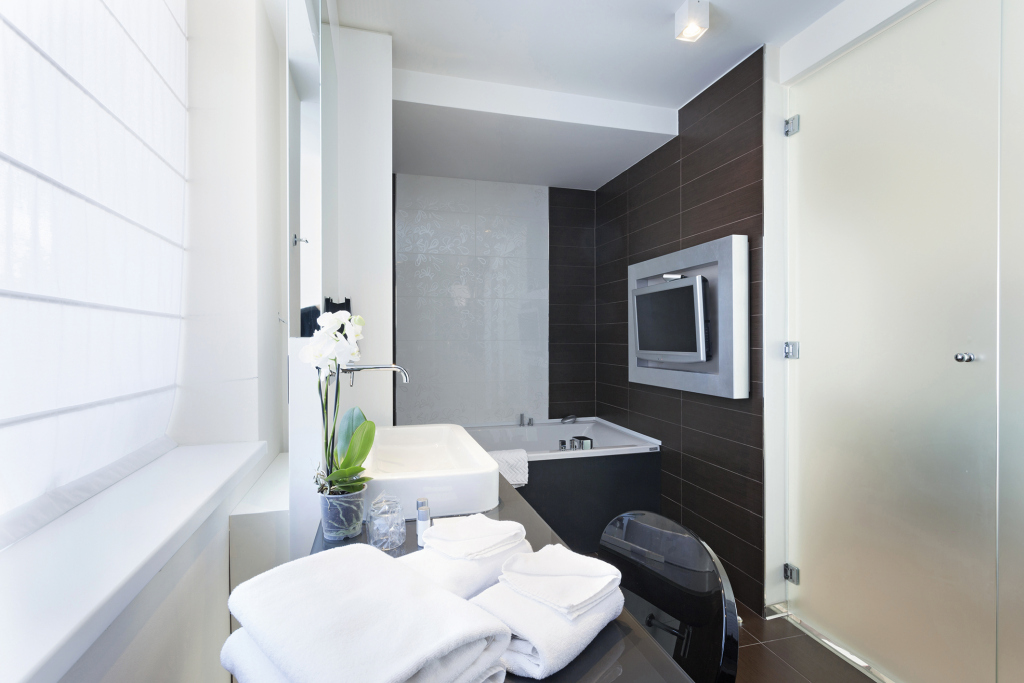 Modernes und komfortables Badezimmer mit Badewanne, Waschbecken, Ablage, Stuhl und TV