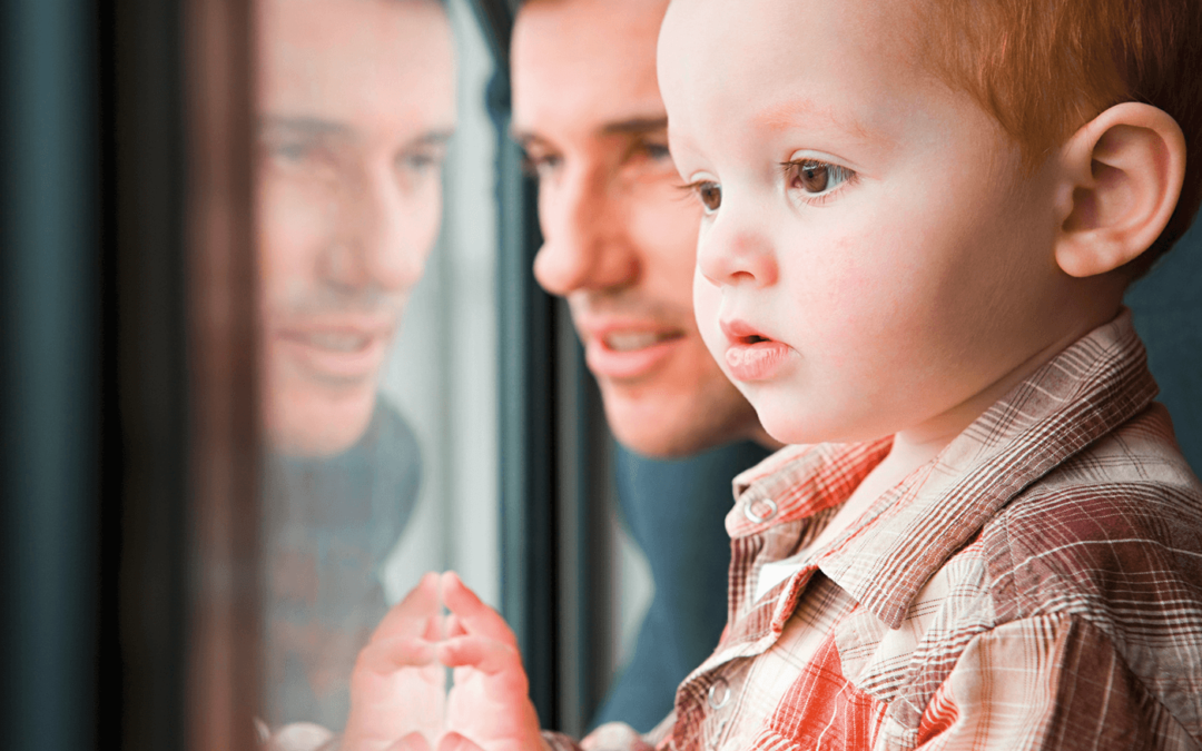 Vater und kleiner Sohn sehen aus einem Fenster.