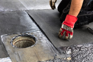 Ein Handwerker repariert eine undichte Stelle auf einem Flachdach