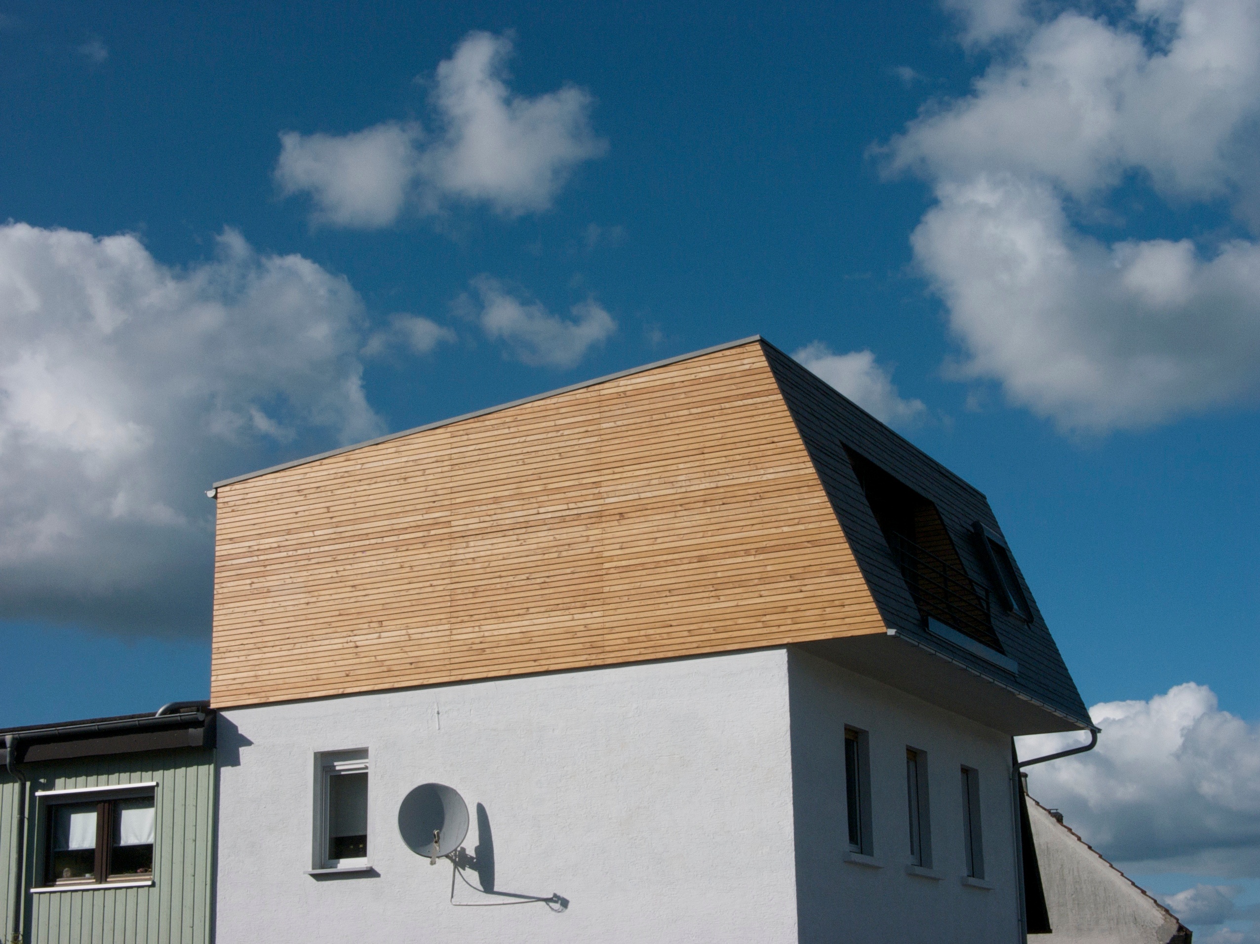 Moderner Dachausbau mit Dachaufstockung und Holzverkleidung eines Wohnhaus.