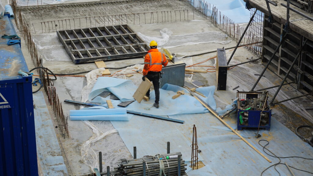 Bauarbeiter arbeiten auf einer Baustelle. Tipps für Baufamilien. Souterrain fest einplanen.