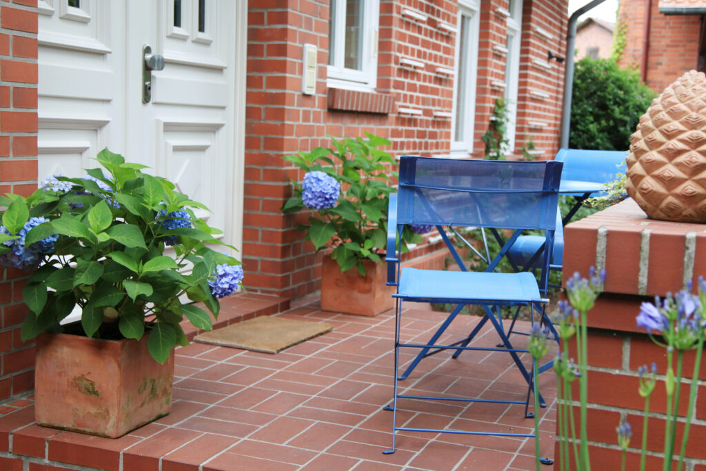 Blauer Gartenstuhl mit Hauseingang im Hintergrund (Fliesen auf Balkon und Terasse) 