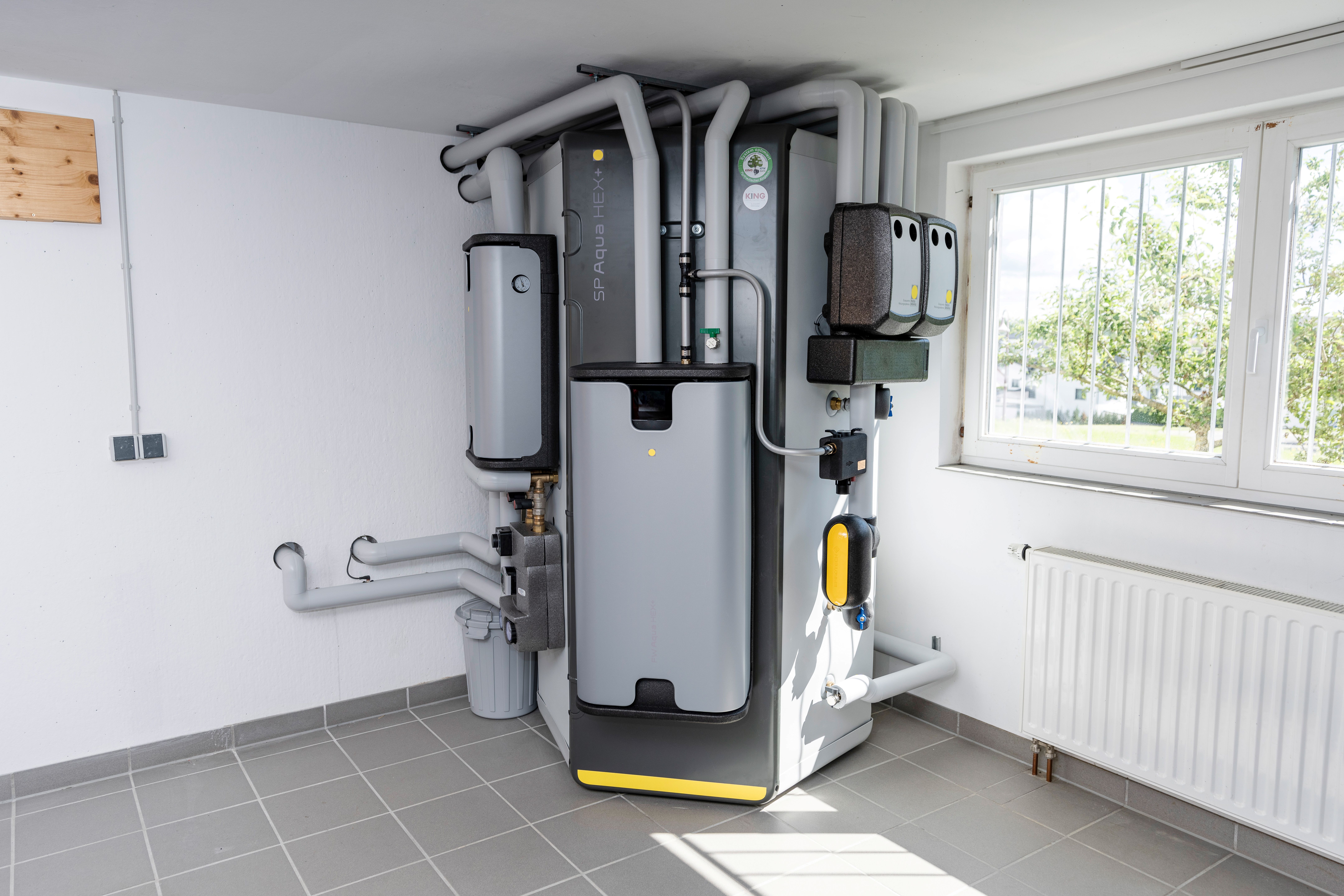 Heiztechnik mit Pufferspeicher und Solarunterstützung Moderner Pufferspeicher mit Solaranbindung in hellem Heizungsraum